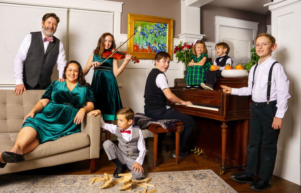 A group gathered in a living room with a piano, coordinated in green outfits for a portrait.