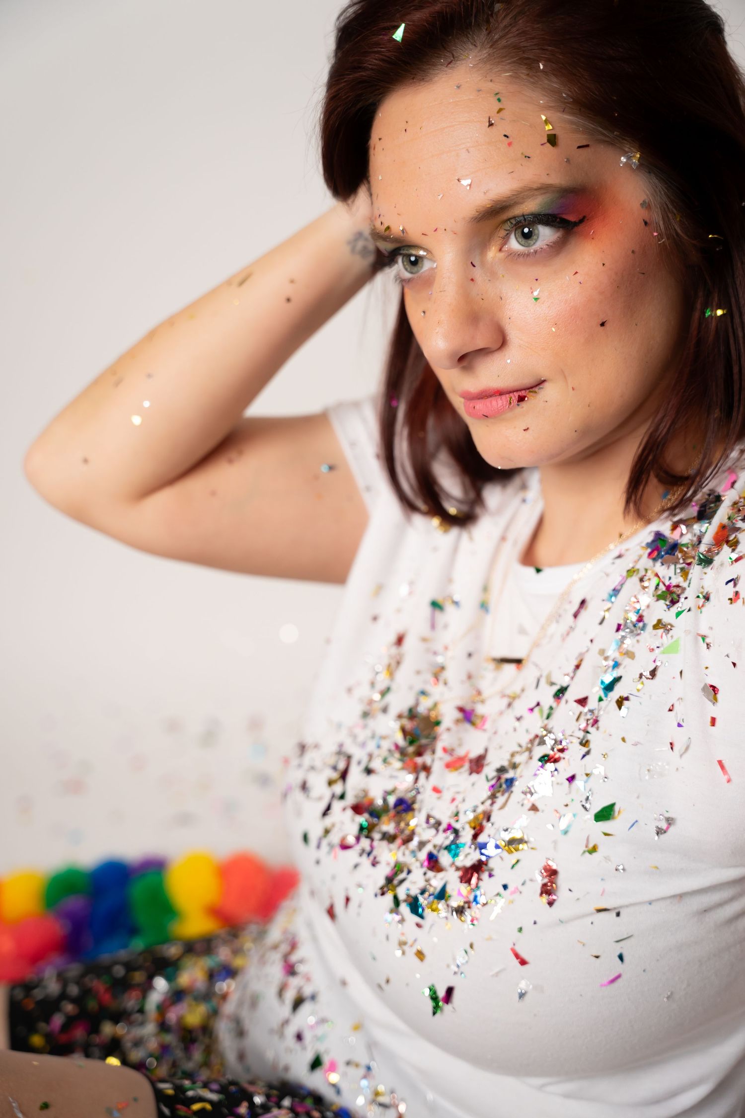 Creative portrait series with white top and colorful glitter confetti against light background.