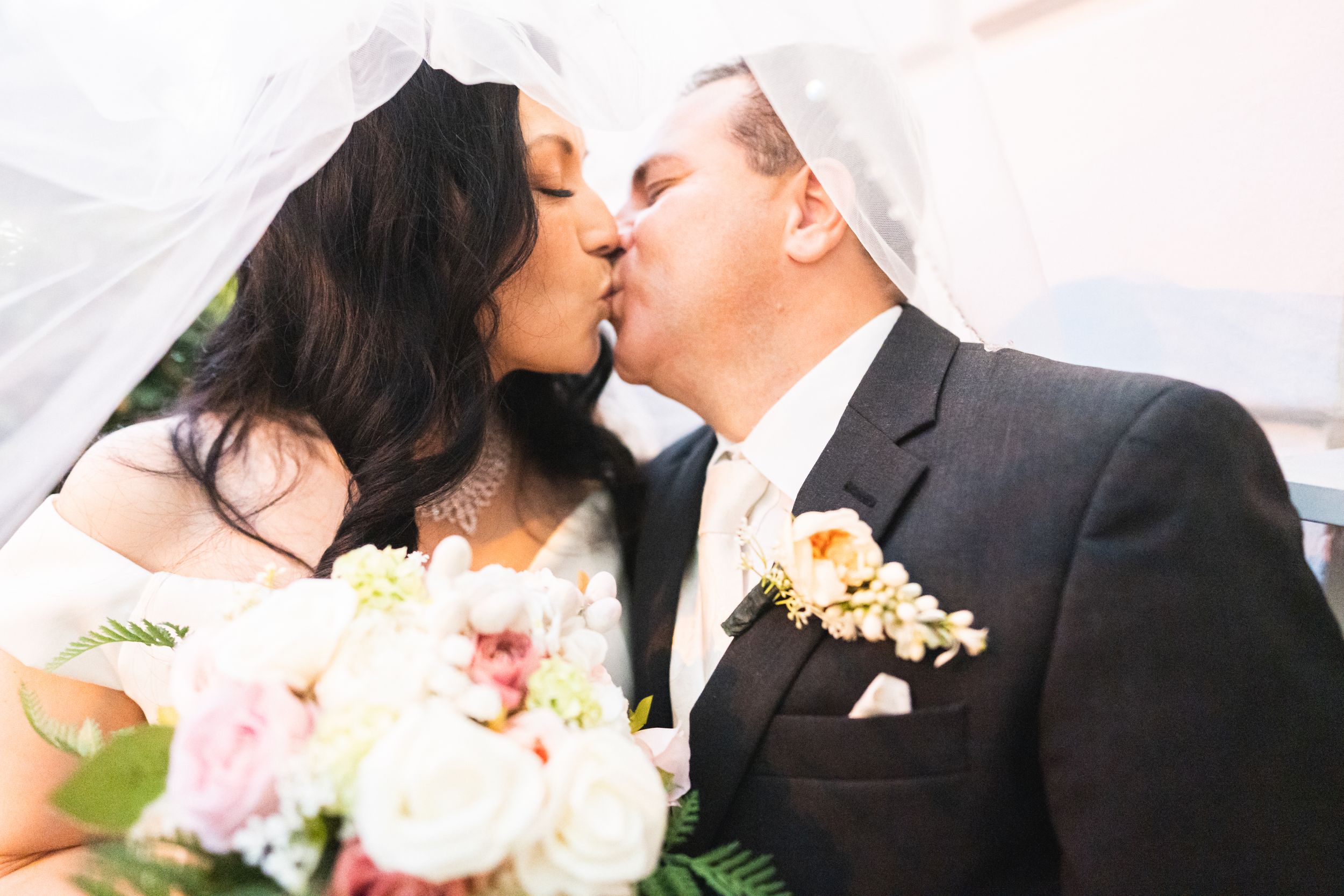 Close-up of romantic moment with white floral bouquet in foreground.