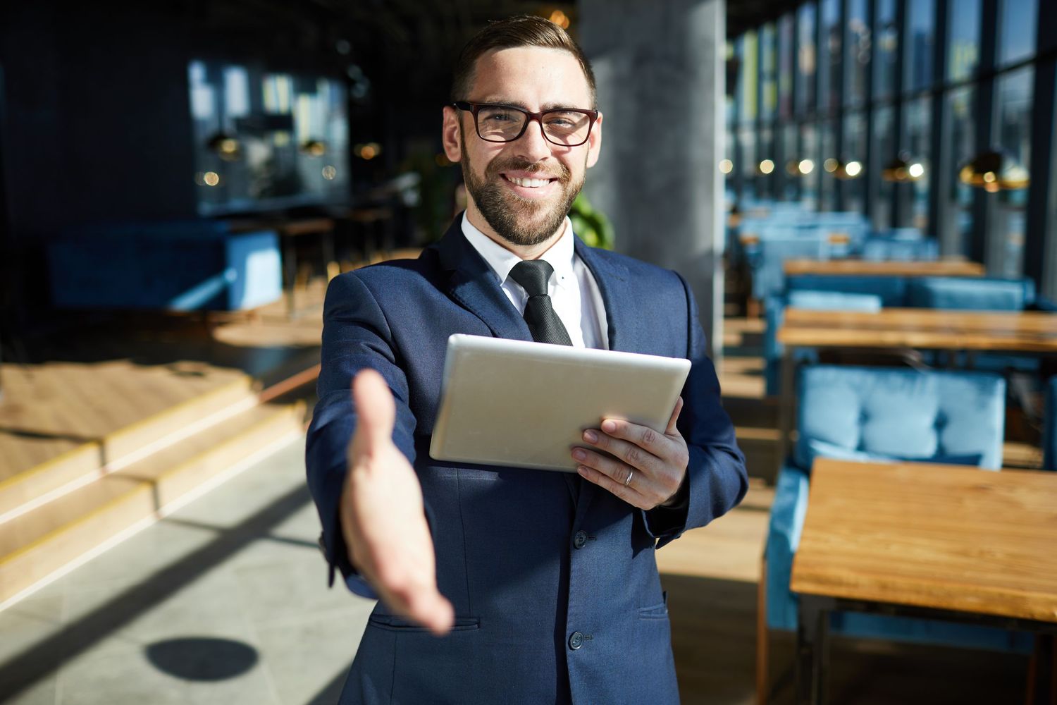A man in a suit reaching out his hand to greet you