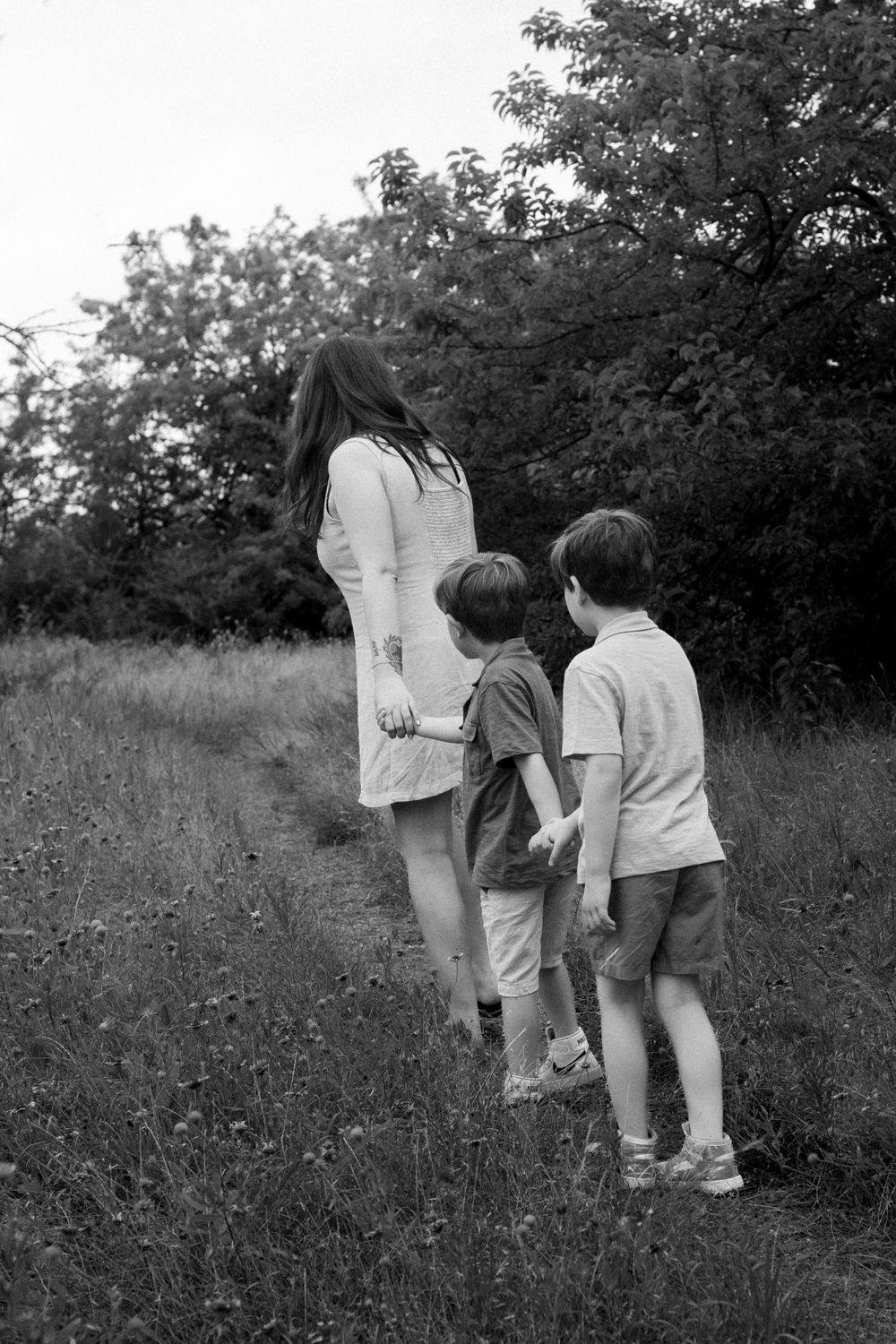 Black and white photo of three people exploring nature path together.