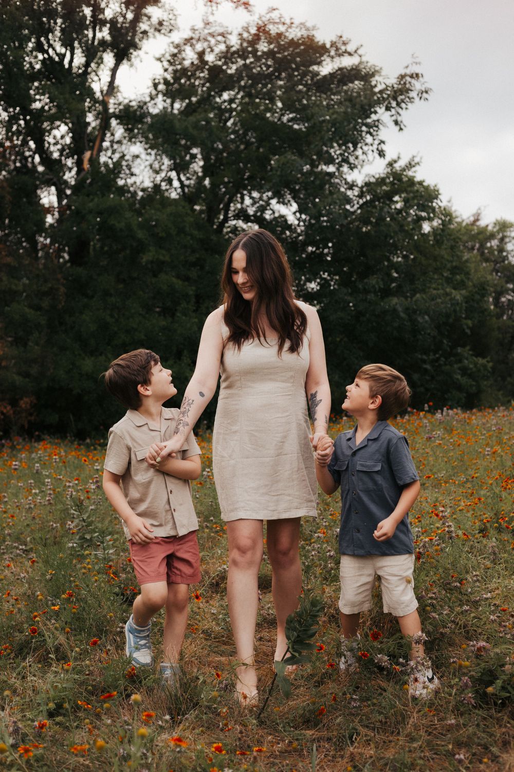 Family walking together through a field of orange wildflowers on a summer day.