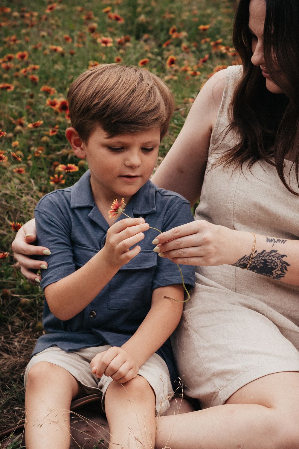 Outdoor moment showing child and parent sitting among orange wildflowers.