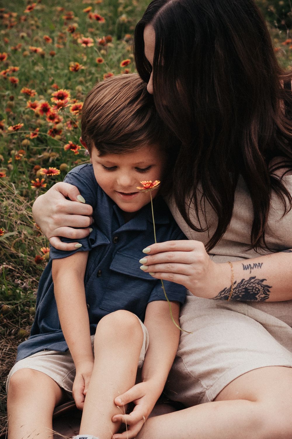 Intimate moment between parent and child sitting in a field of orange wildflowers.
