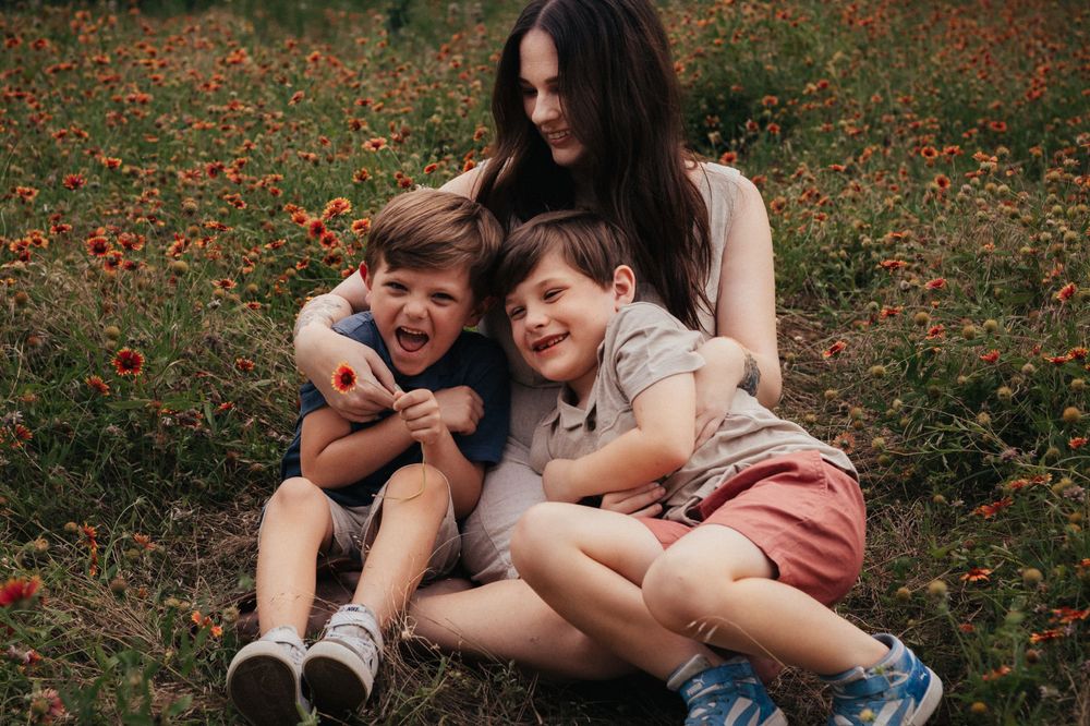 A joyful family moment sitting together in a field of orange wildflowers on a sunny day.