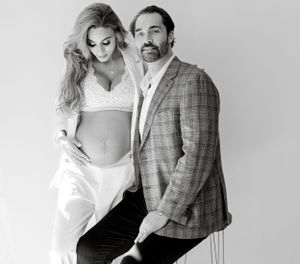 Intimate black and white maternity portrait of couple in plaid blazer and white outfit.