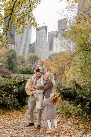 Family enjoying autumn day in Central Park with NYC skyline in background.