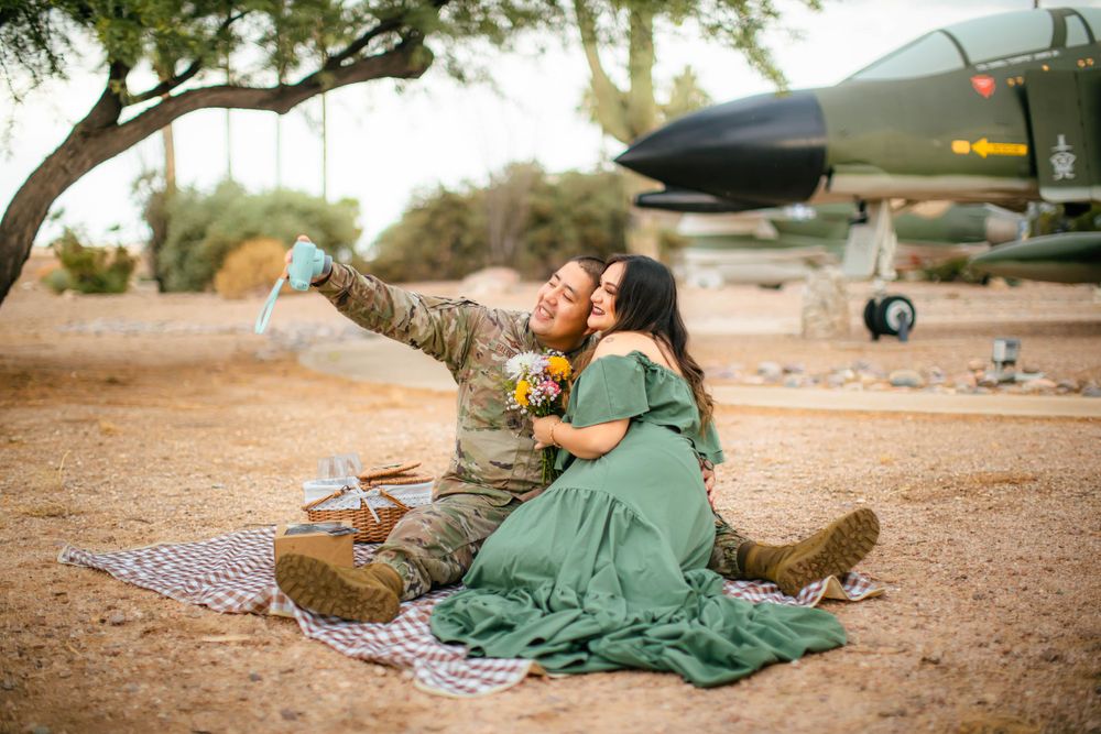 Military-themed picnic setup near vintage aircraft with blanket and props.