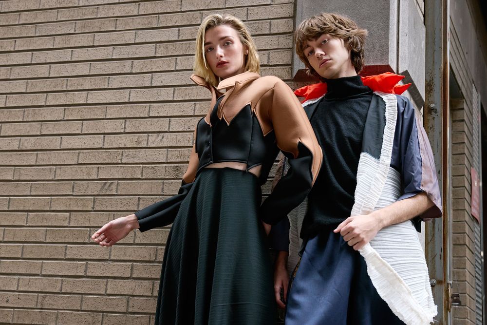 A group of students pose in a fun manner against a brick wall at school.
