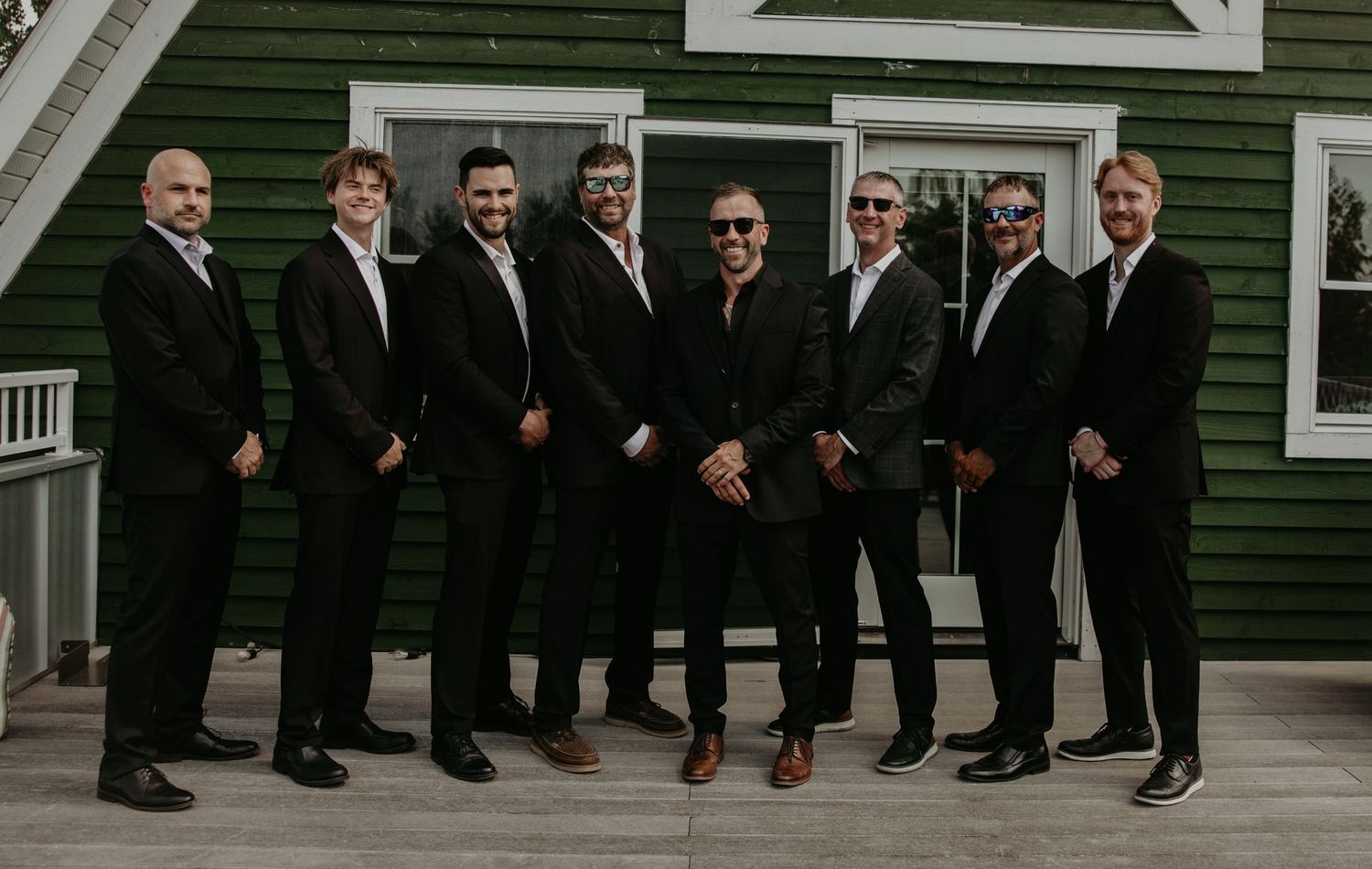 Groomsmen in black suits showing off colorful socks in creative wedding photo.
