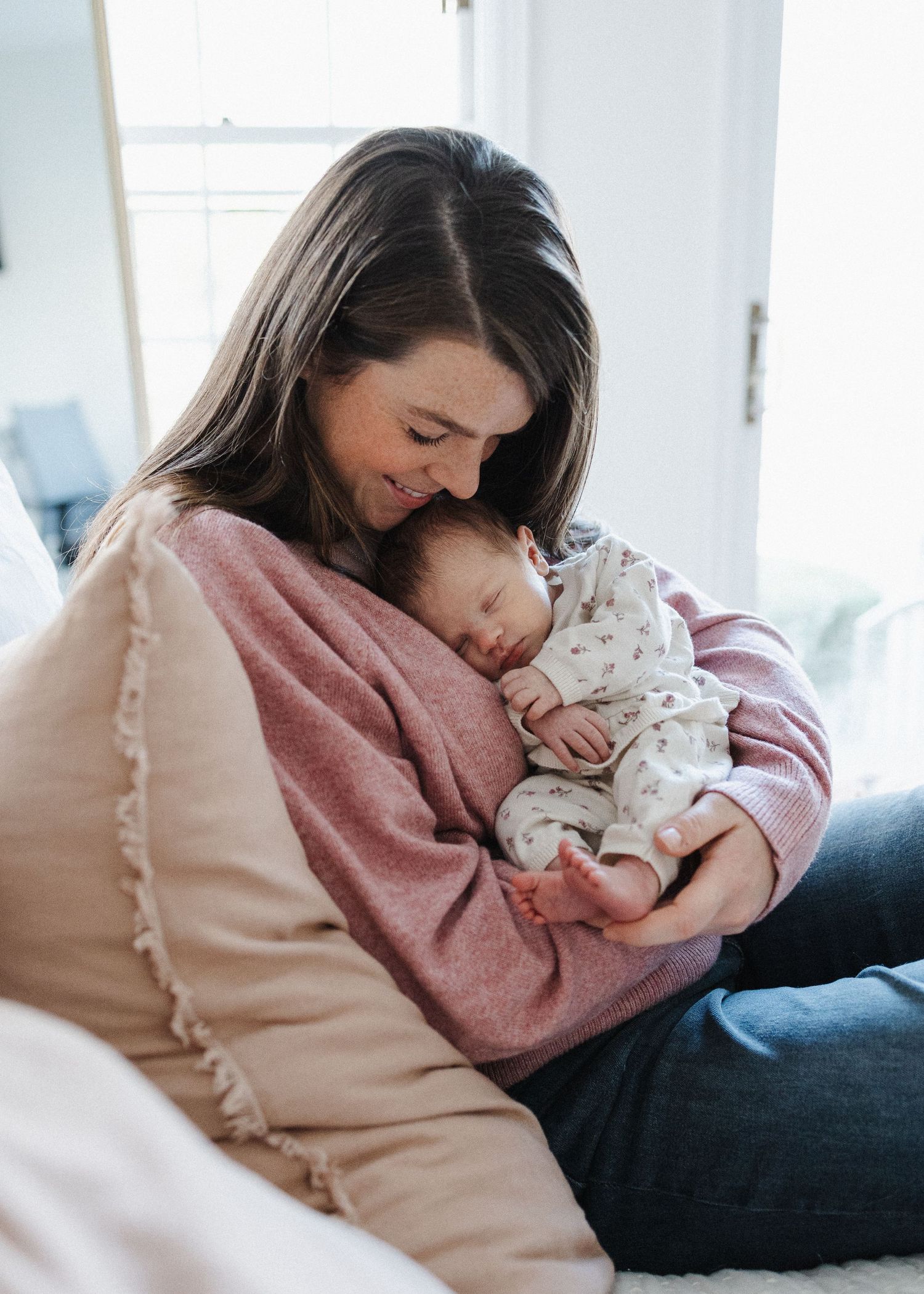 Intimate family moment with newborn baby on white bedding.
