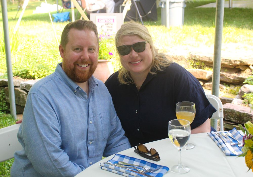 Two guests enjoying drinks and conversation at an outdoor table setting.