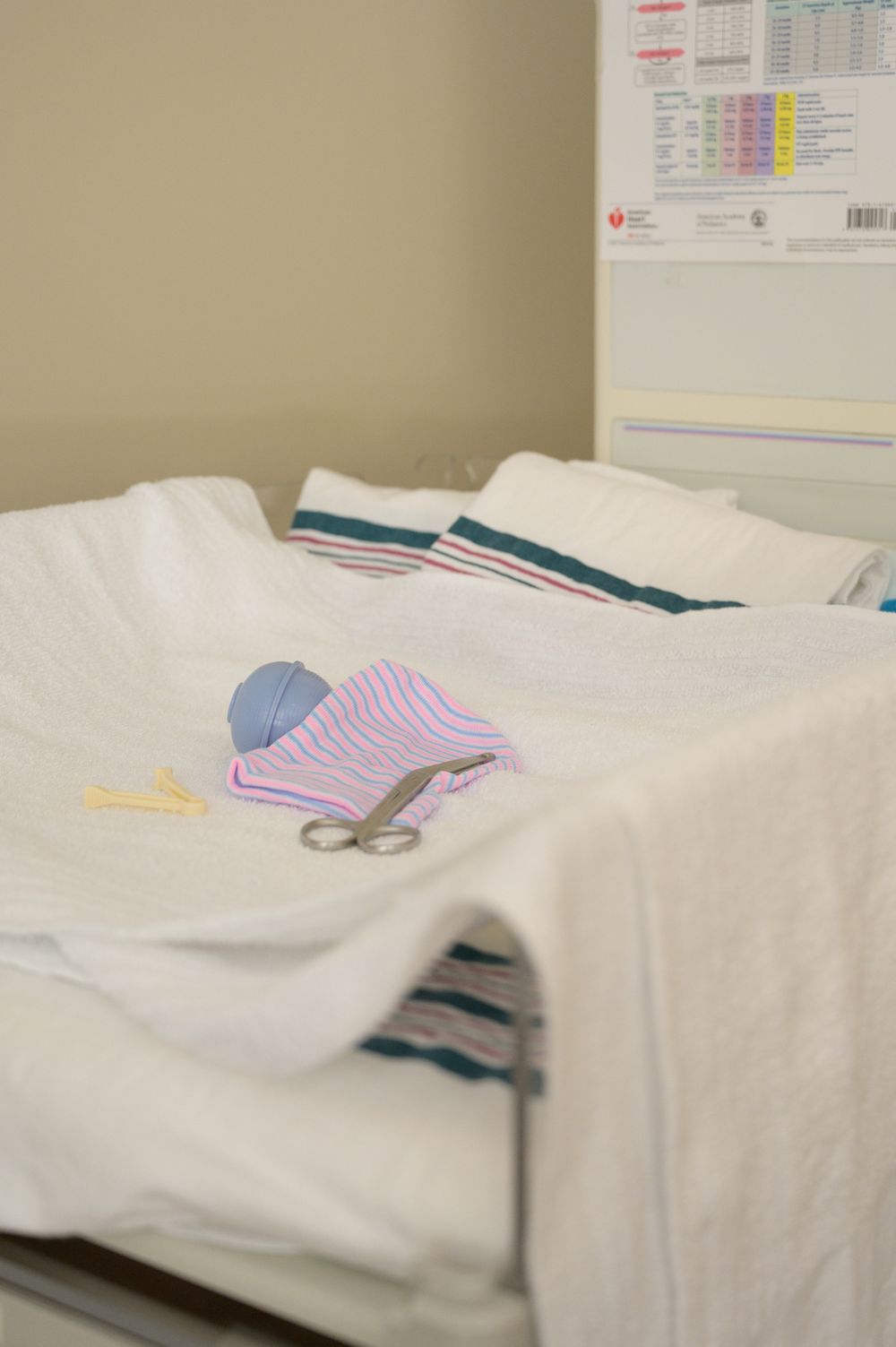 Medical supplies and blankets arranged on a hospital bed with blue and pink items visible.