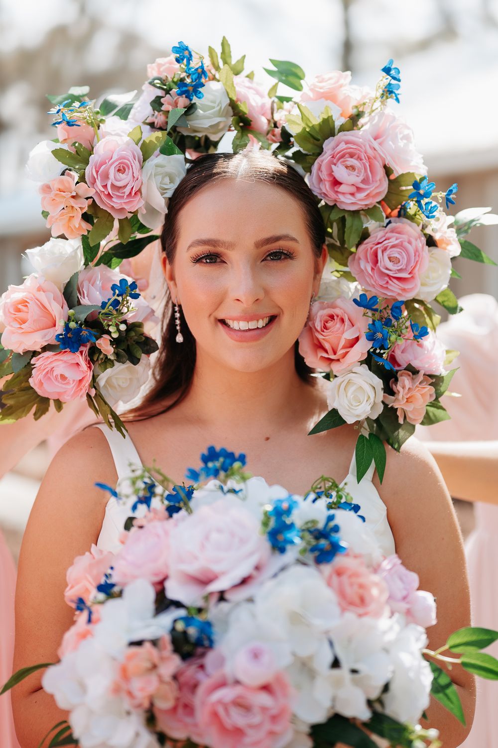 Beautiful bridal portrait with pink and white roses and bright blue delphinium flowers in crown and bouquet.