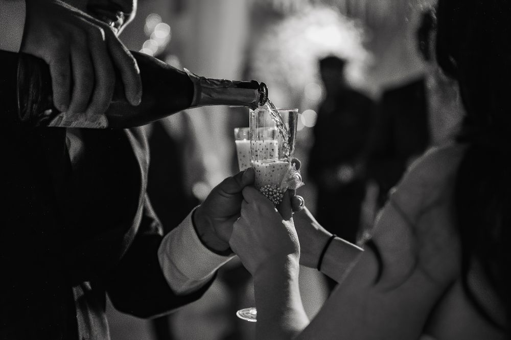 Black and white photo of hands pouring champagne into crystal glasses at an elegant celebration.
