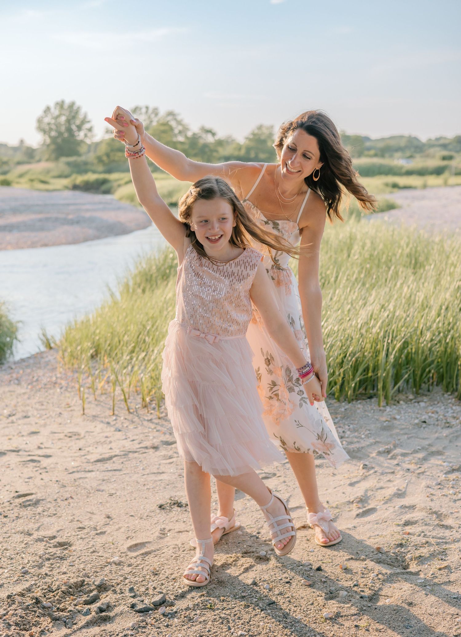 Two people dancing and laughing together on coastal path during golden hour.