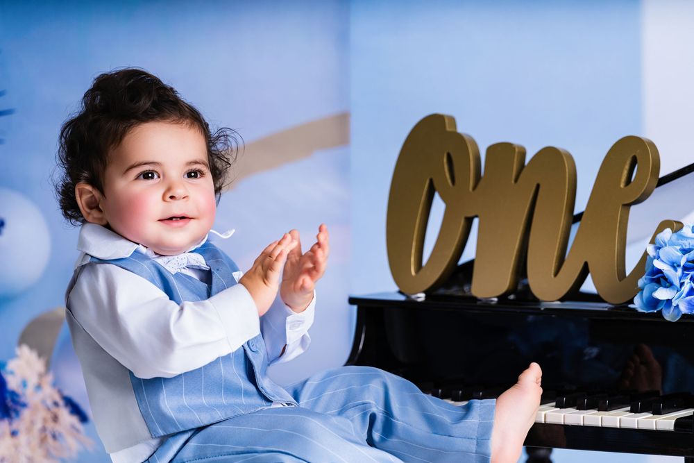 Stylish first birthday photo setup featuring a piano and blue balloon arrangement.