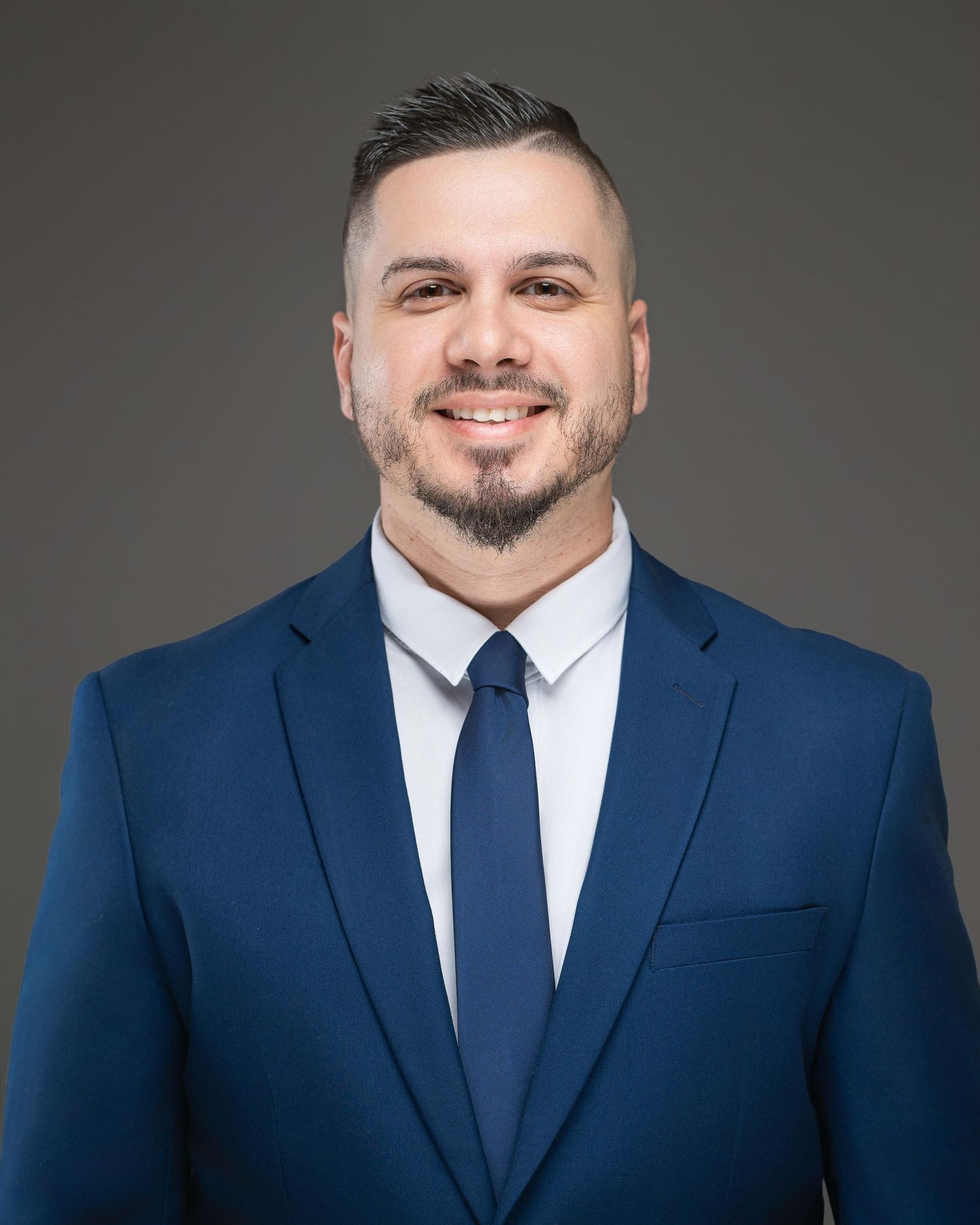 Professional headshot of someone in a navy blue suit and tie against a dark grey background. Prospect Farm GA. Kelly Photography Atlanta.