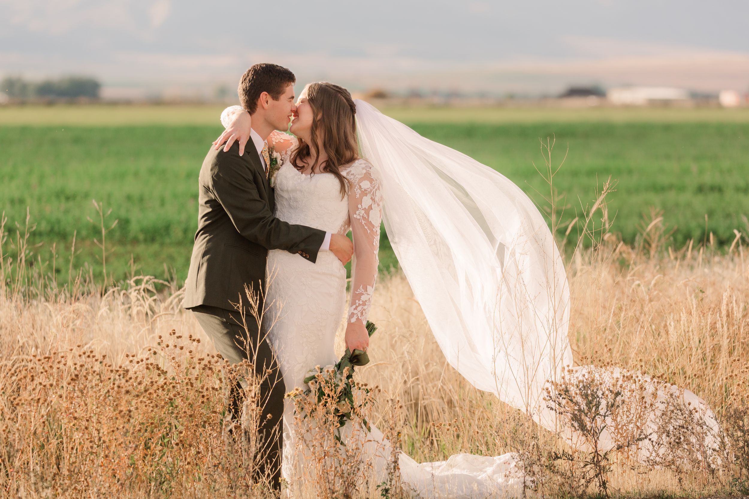 A romantic couple embraces in a golden wheat field at sunset.