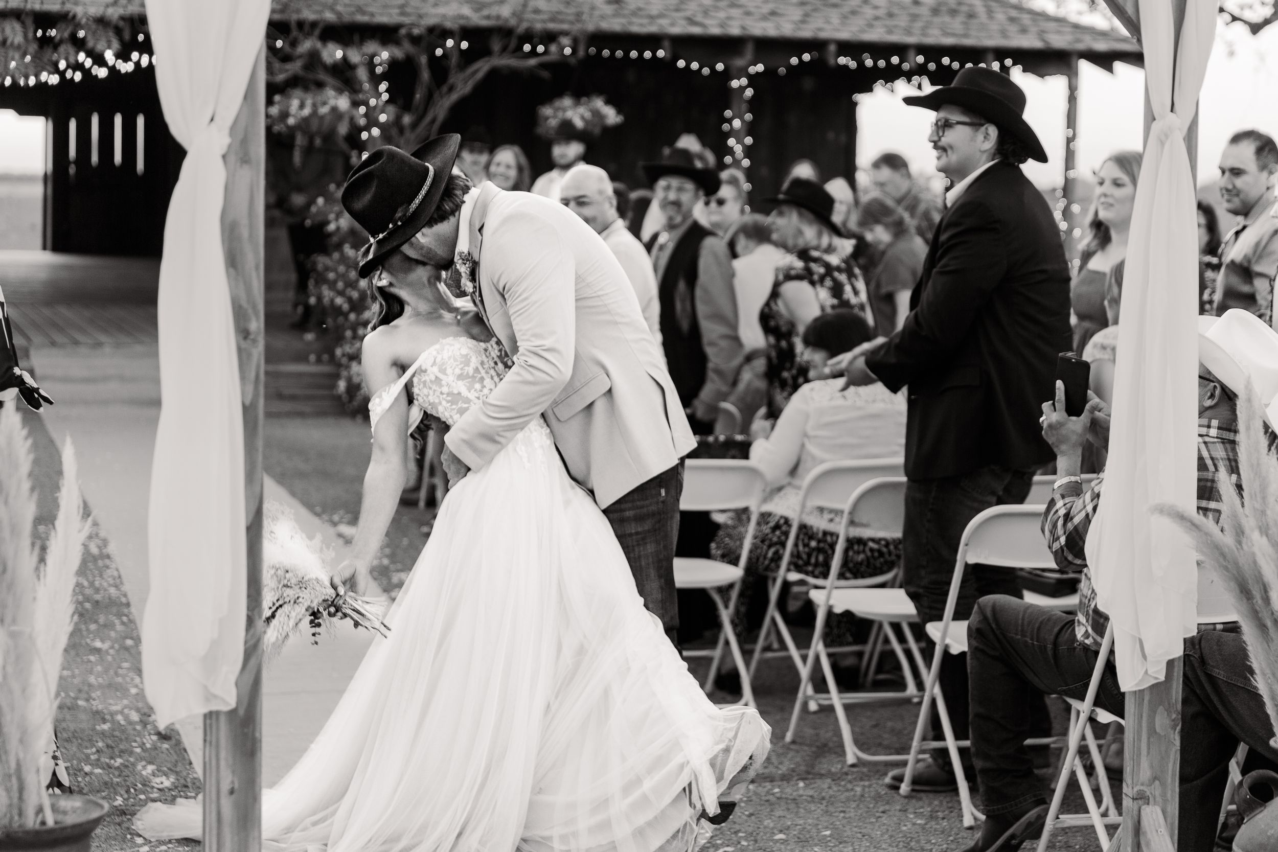 Wedding reception under string lights with guests dancing and celebrating.
