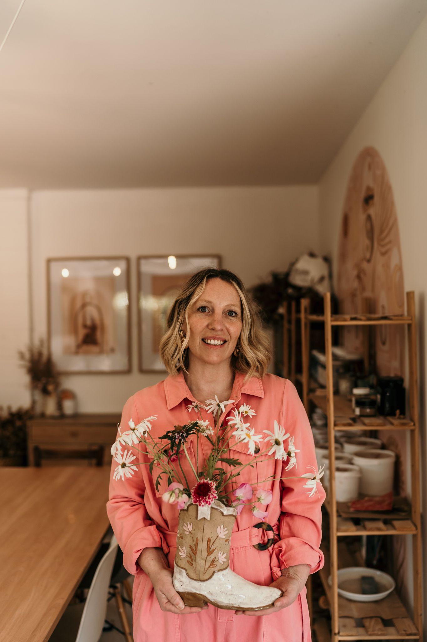 Someone in a pink floral jacket holding dried flowers in a pottery studio in Christchurch.