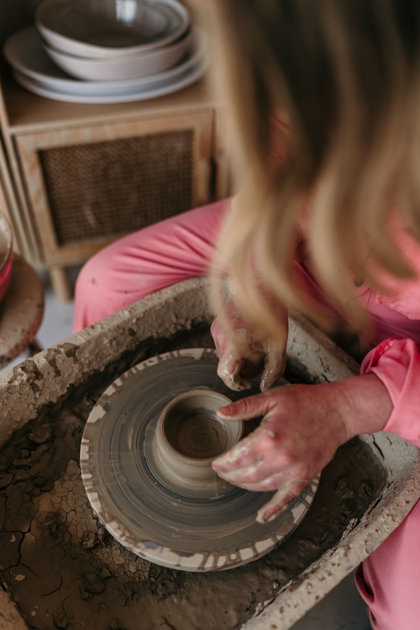 Hands working with clay on a pottery wheel creating a ceramic vessel in Christchurch.