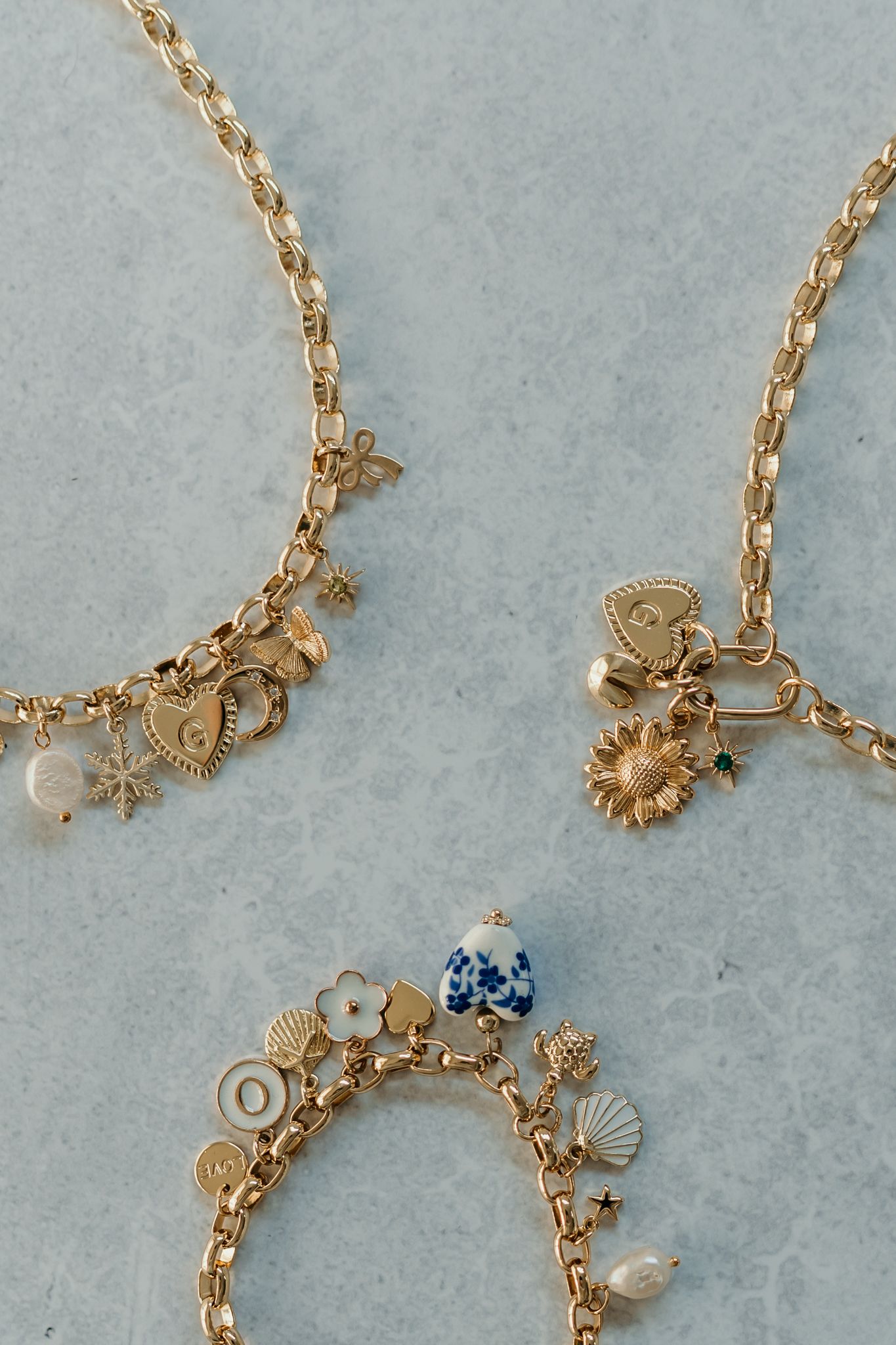 A delicate gold charm necklace featuring seashells, stars, and ocean-themed pendants on a dainty chain.
