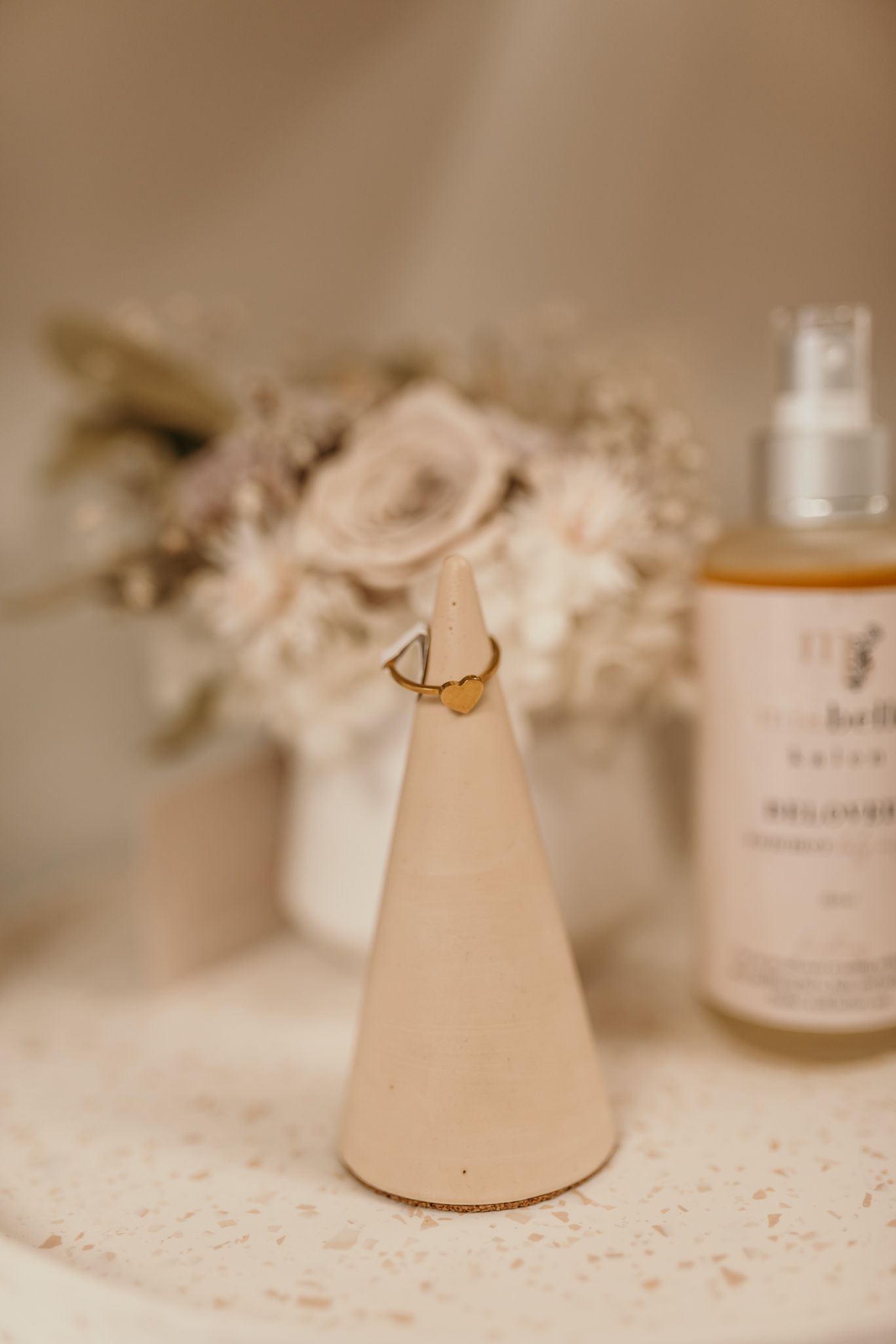 Ring cone holder with dried flowers and beauty product bottle in a soft neutral setting in Christchurch shop.