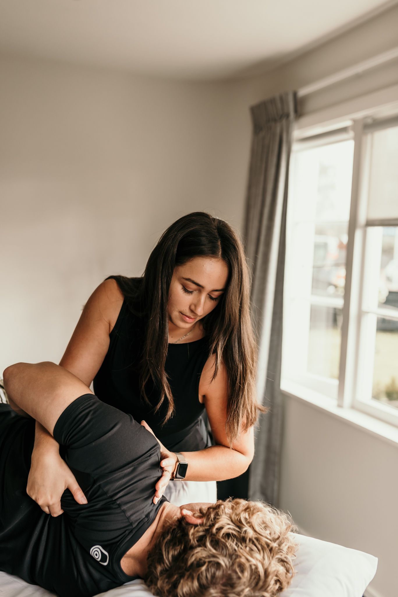 Healthcare professional performing physical therapy treatment in a bright room in Christchurch.