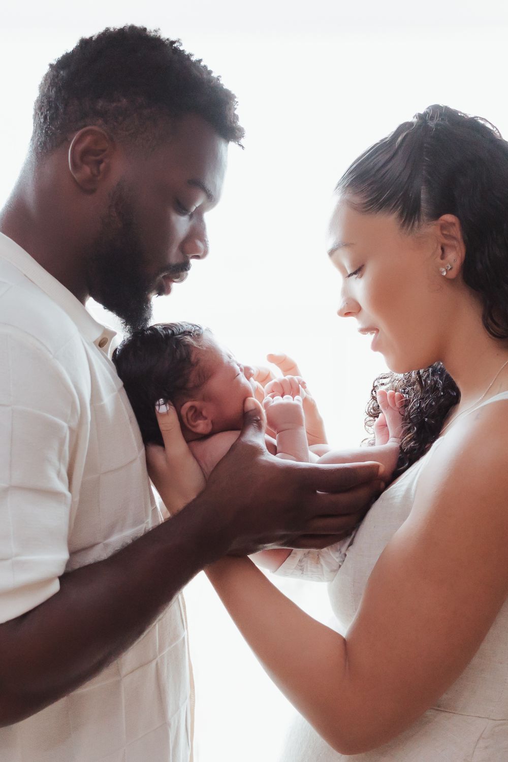 a man and woman are both standing close and holding their small baby between their bodies