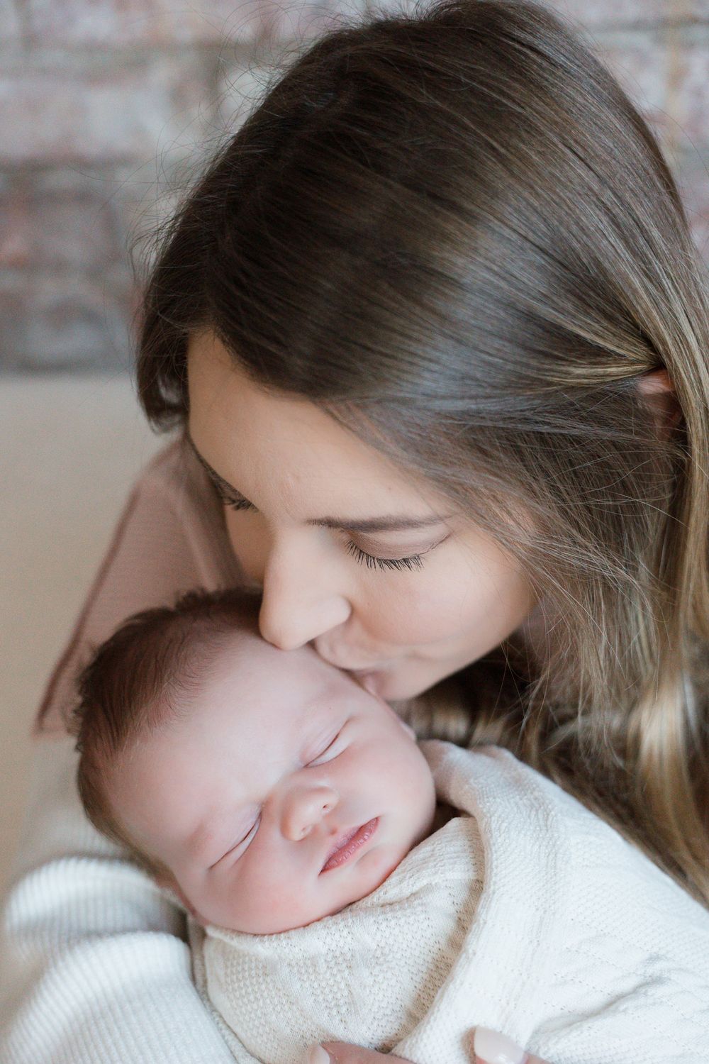 A woman kisses her sleeping babies cheek