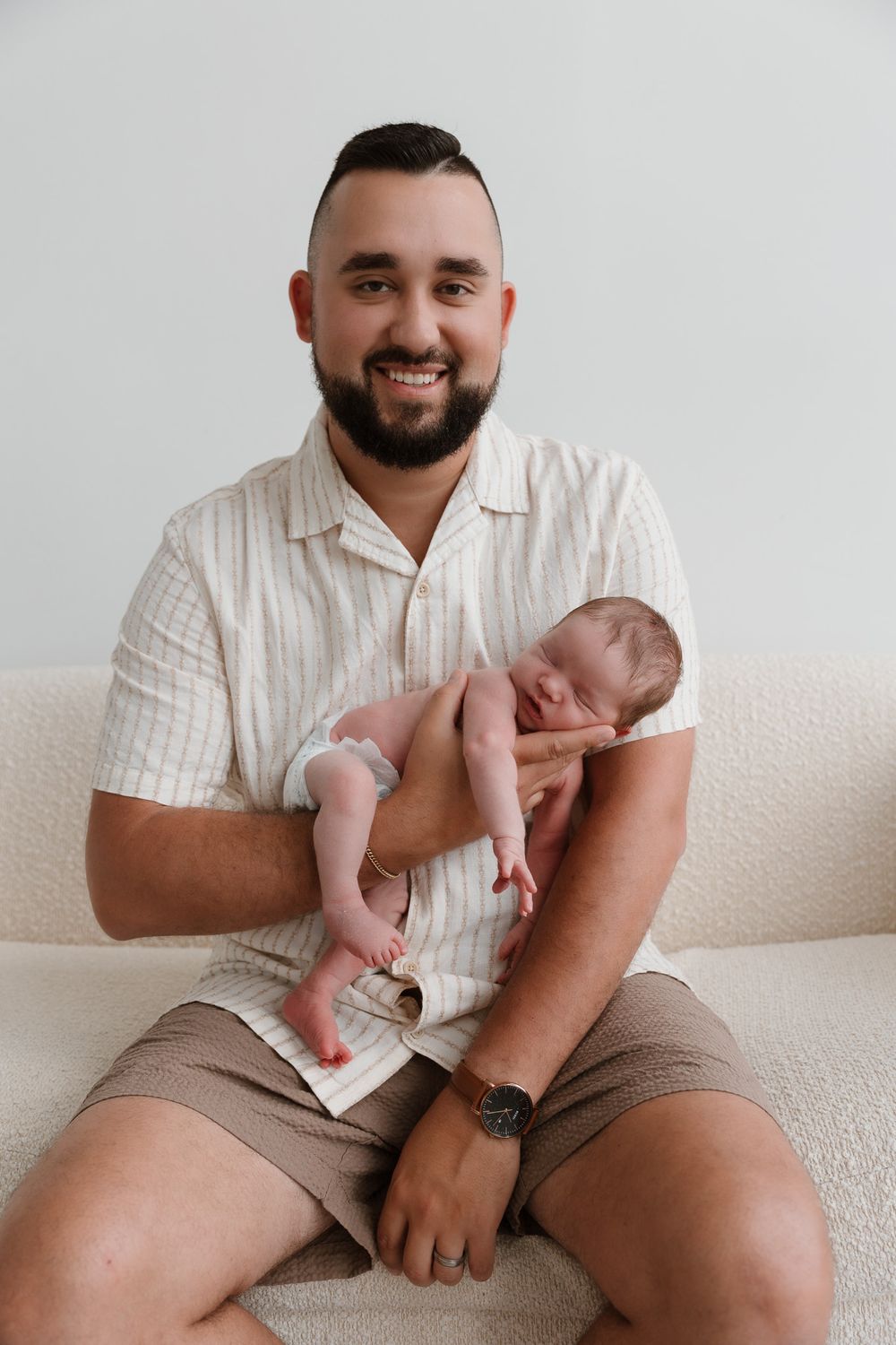A man holds his sleeping baby, baby is cradled in the man's hand
