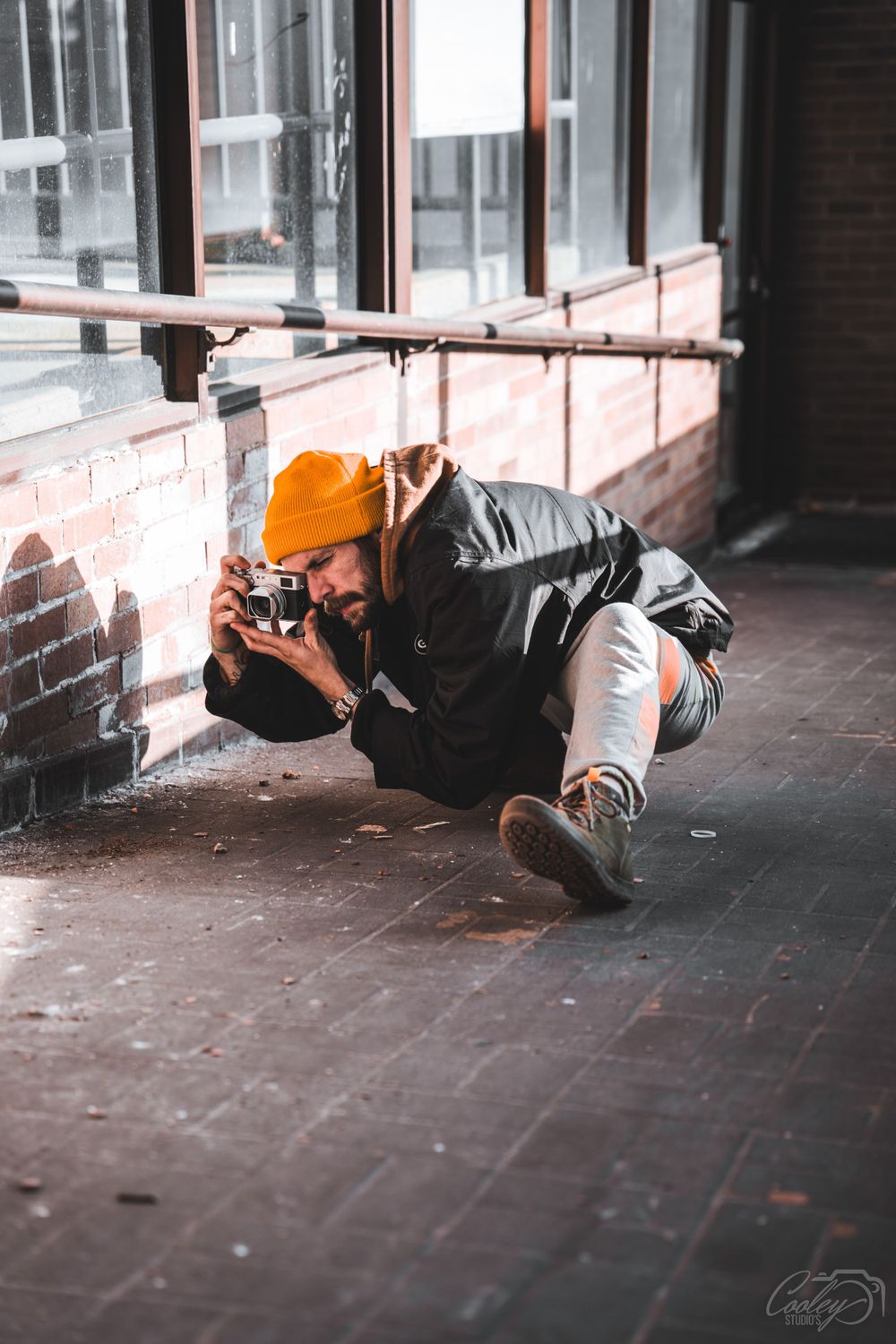Dedicated photographer lying on ground to capture low-angle shots with vintage camera indoors.