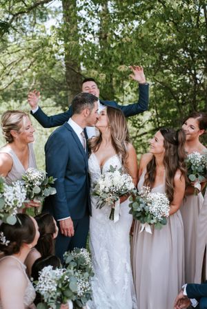Wedding celebration with bridesmaids holding white bouquets amid lush greenery.
