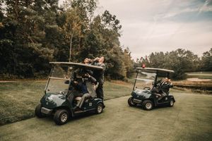 Wedding guests riding in golf carts along a path on a golf course.