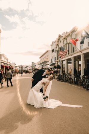 Dramatic wedding dip kiss on a historic small town street with American flag in background.