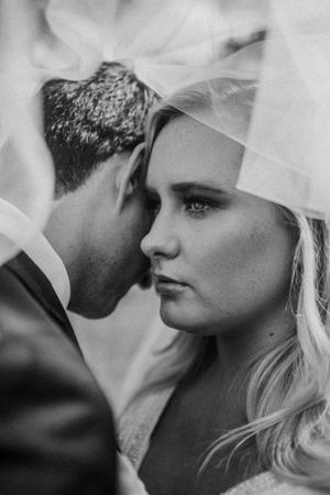 Intimate black and white wedding portrait with ethereal veil detail.