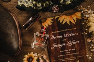 Wedding invitation and perfume bottle nestled among sunflowers and decorative elements.