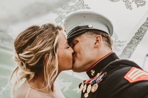 A military wedding kiss captured with decorative details in the background.