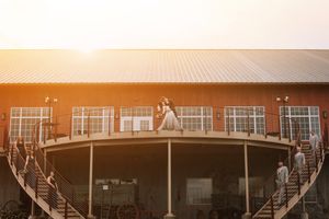 A wedding couple standing on a balcony during golden hour at a rustic venue.