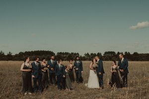 A wedding party poses together in a golden autumn field.