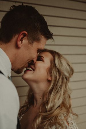 An intimate moment between a couple sharing laughter against a white wall background.