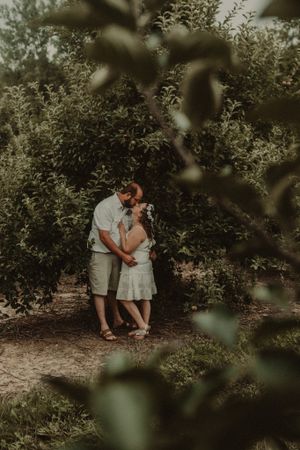 An intimate romantic moment captured through foliage in a garden setting.