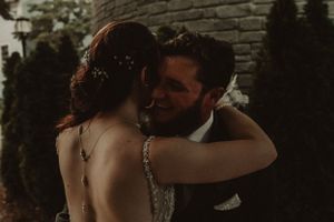 Intimate moment between newlyweds against stone wall background.