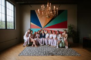 Wedding party group photo with colorful geometric backdrop and chandelier.