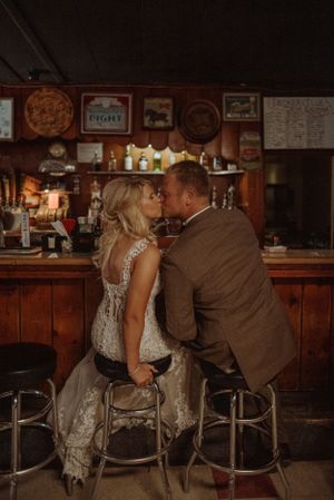 A romantic bar scene with a couple sharing an intimate moment on vintage barstools.