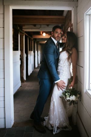 A romantic wedding portrait of a couple in a rustic hallway with white walls.