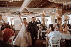 Wedding reception in an industrial venue decorated with string lights and white fabric draping.