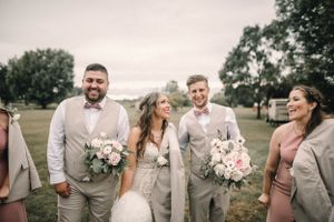 Wedding party in coordinated gray attire shares candid moment outdoors.
