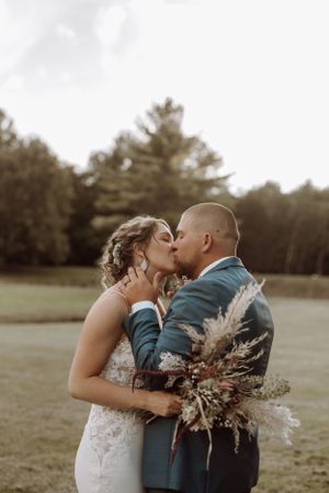 Intimate wedding moment captured with dried flower bouquet in golden hour light.